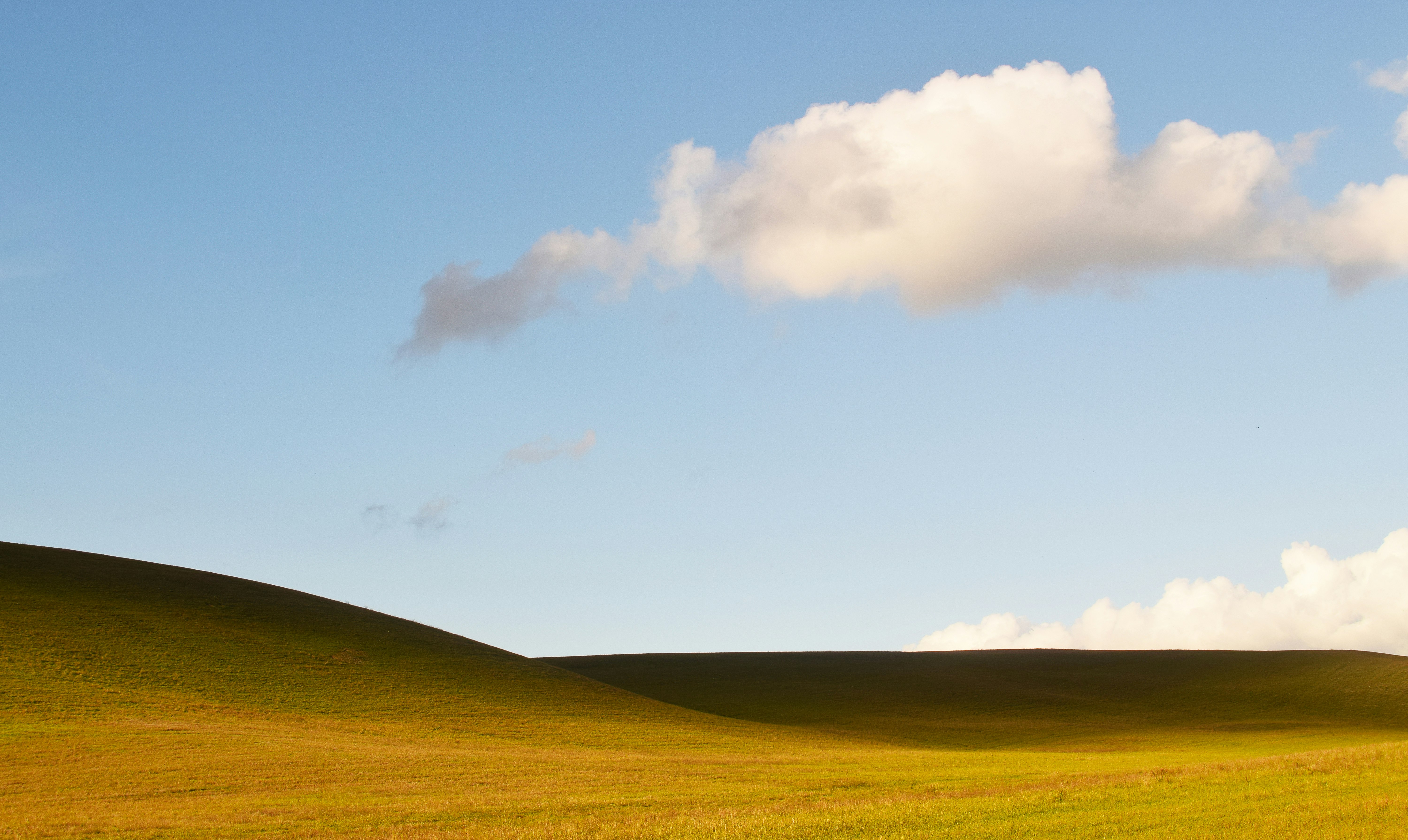 green hills under clouds during daytime